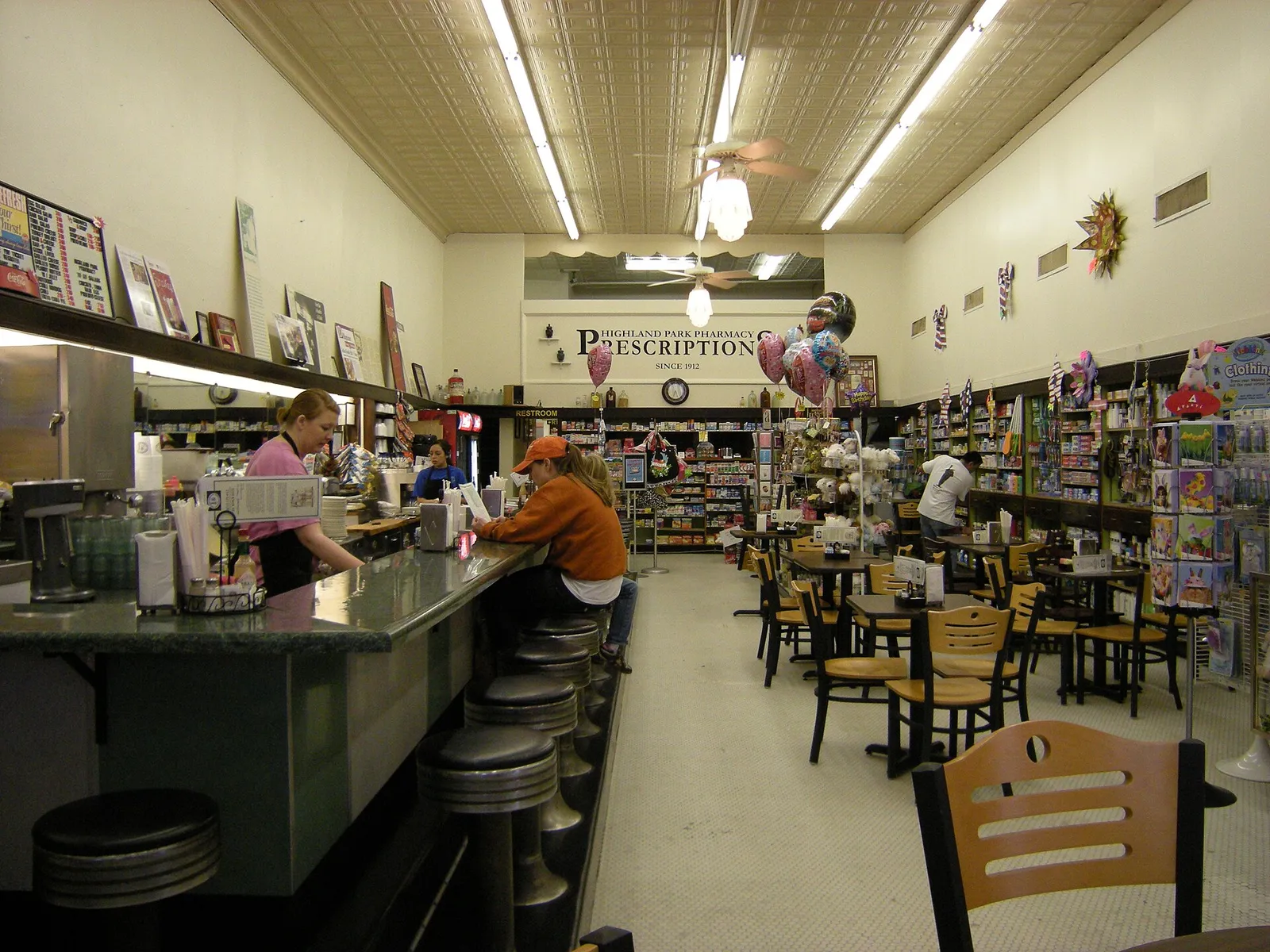 The interior of an independent neighbourhood pharmacy, with a soda fountain counter and shelved stock behind