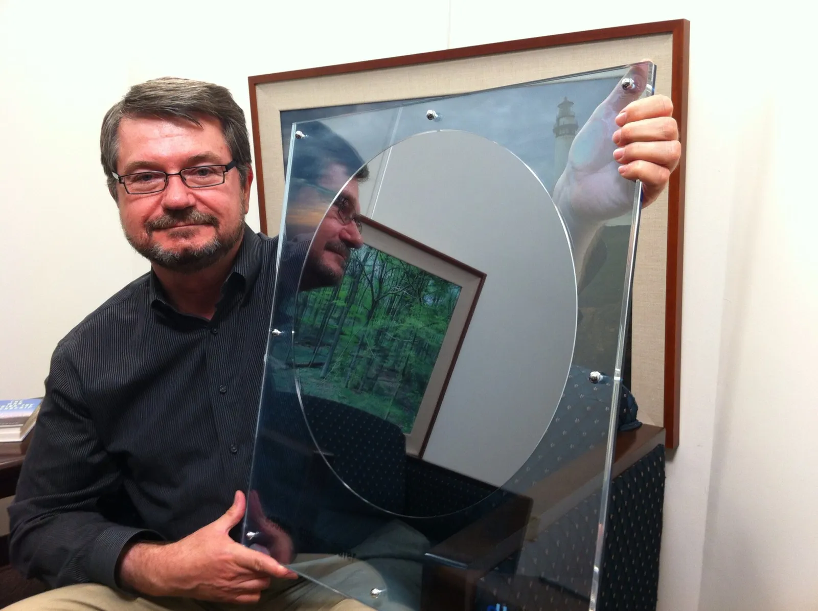 A person holds up a large silicon wafer used to make chips