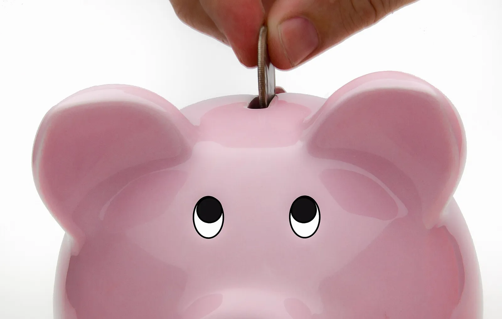 A coin being deposited into a piggy bank