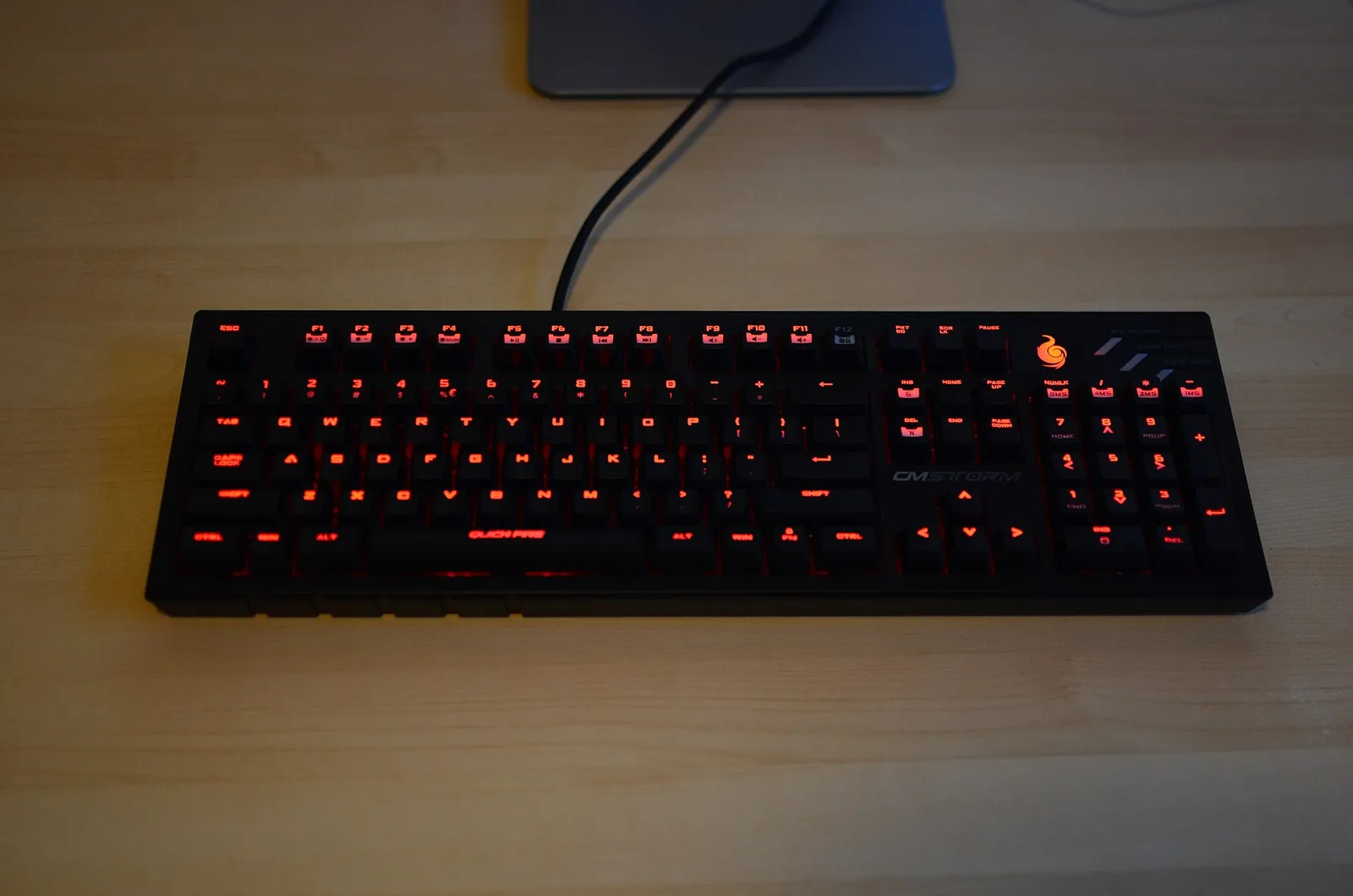 A backlit computer keyboard glowing in the dark