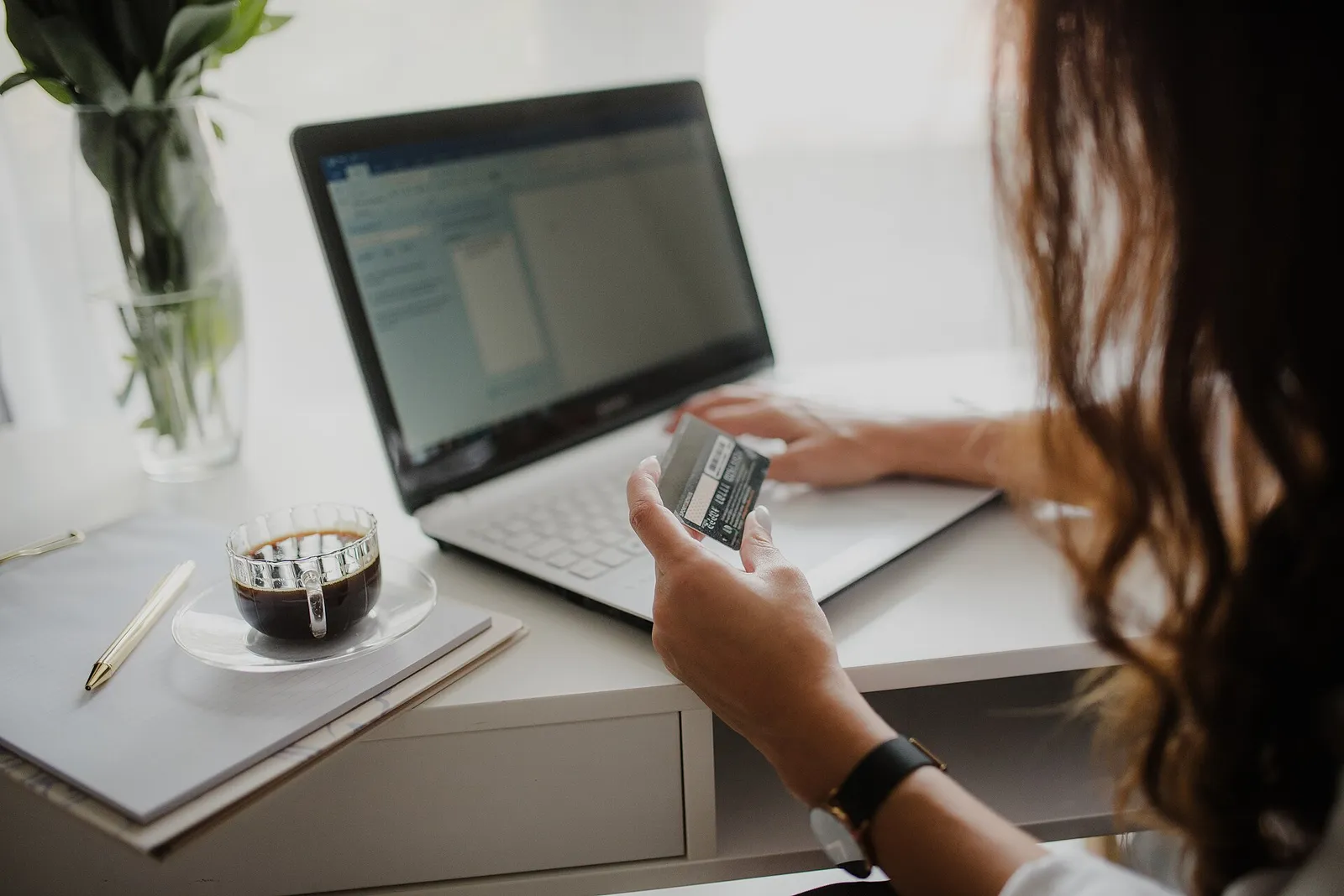 A person holding a credit card while shopping on a laptop