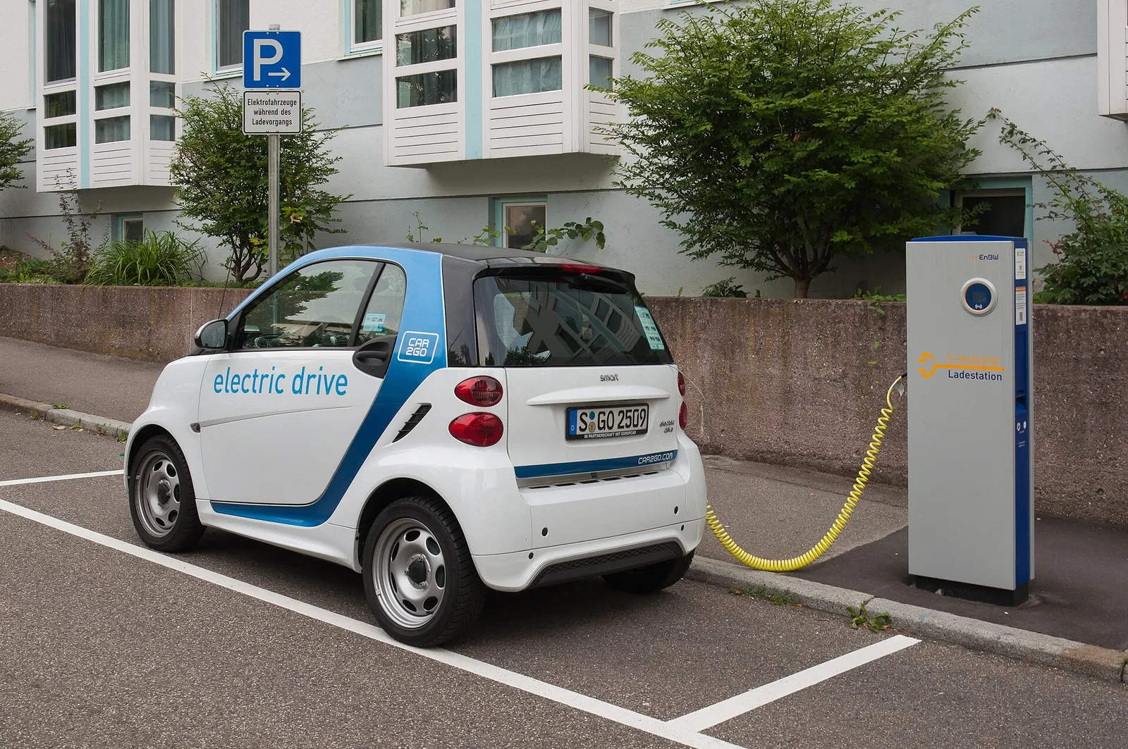An electric car plugged into a kerbside charging point in a marked EV bay in Stuttgart