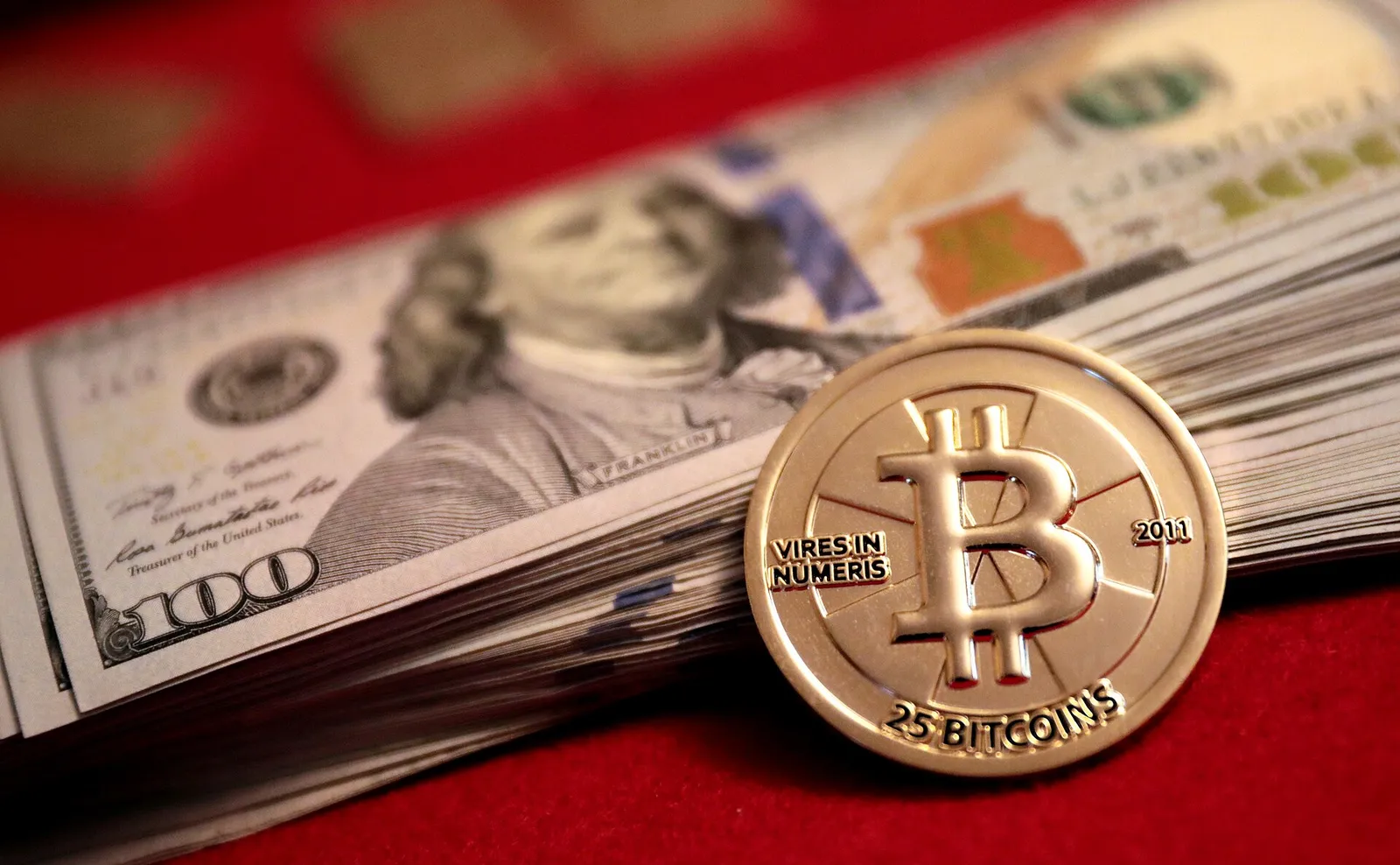US hundred-dollar bills with a physical bitcoin coin
