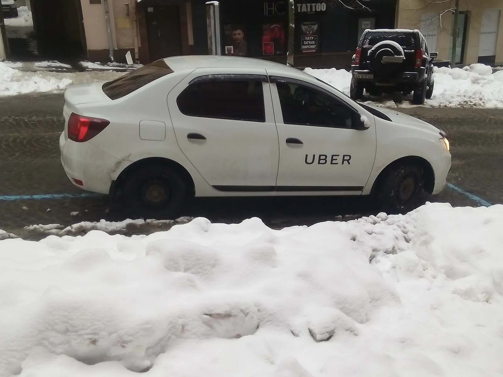 A car displaying an Uber sticker waiting at a city kerbside