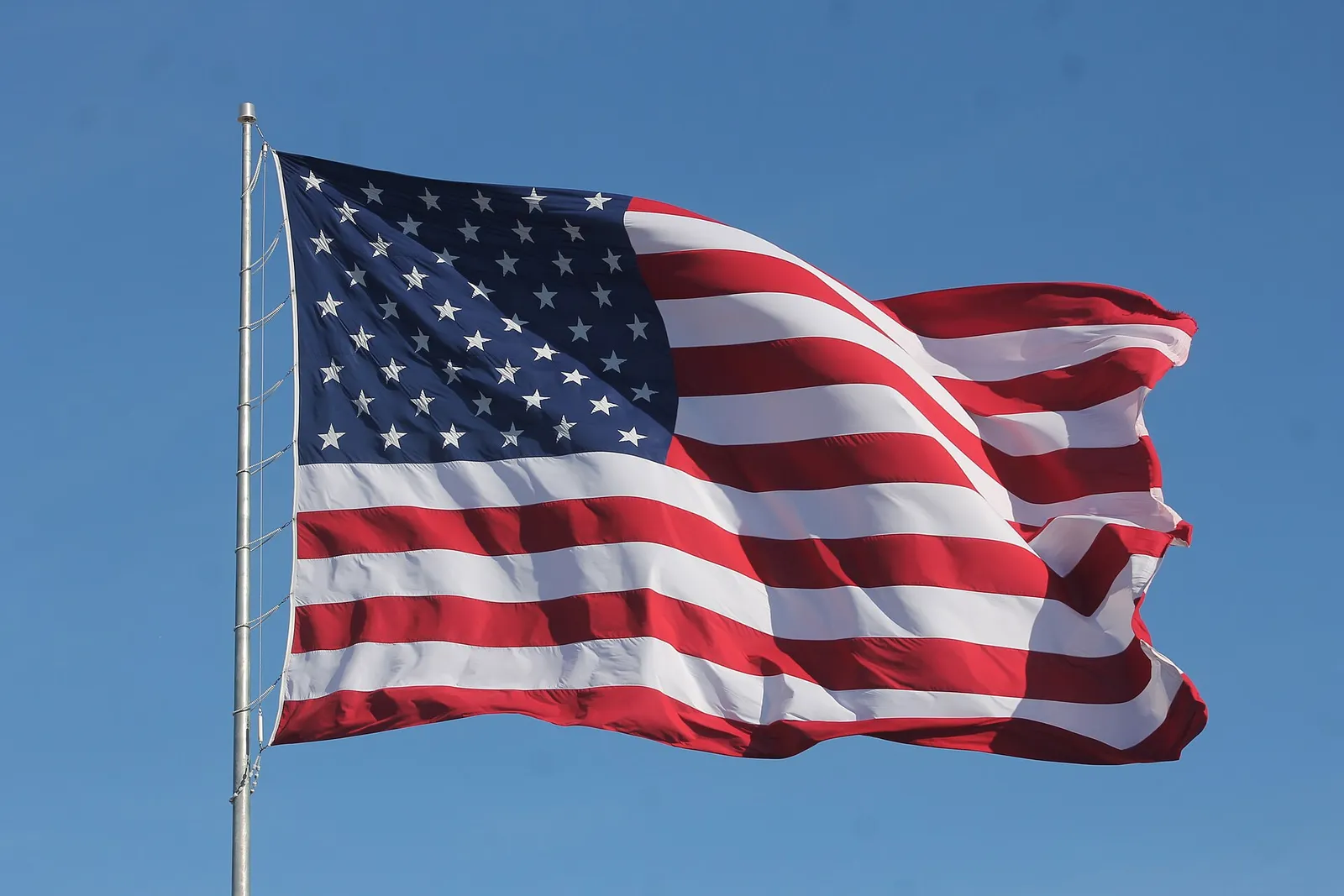 A United States flag waving against a blue sky